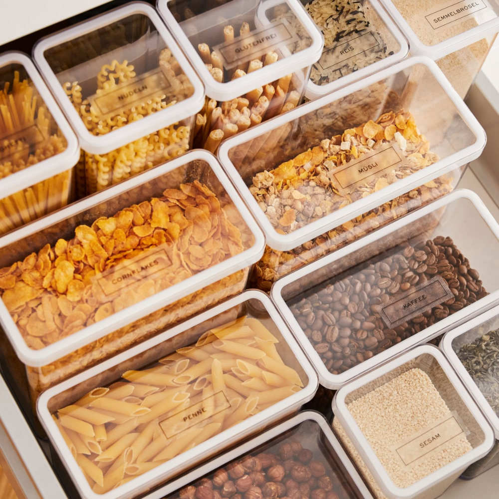 Eine Schublade mit transparenten Behältern, die mit LOFT Aufkleber - Küchenorganisation by Rotho-ideal beschriftet sind, um Ihre Trockenvorräte zu organisieren und alles leicht zu identifizieren.