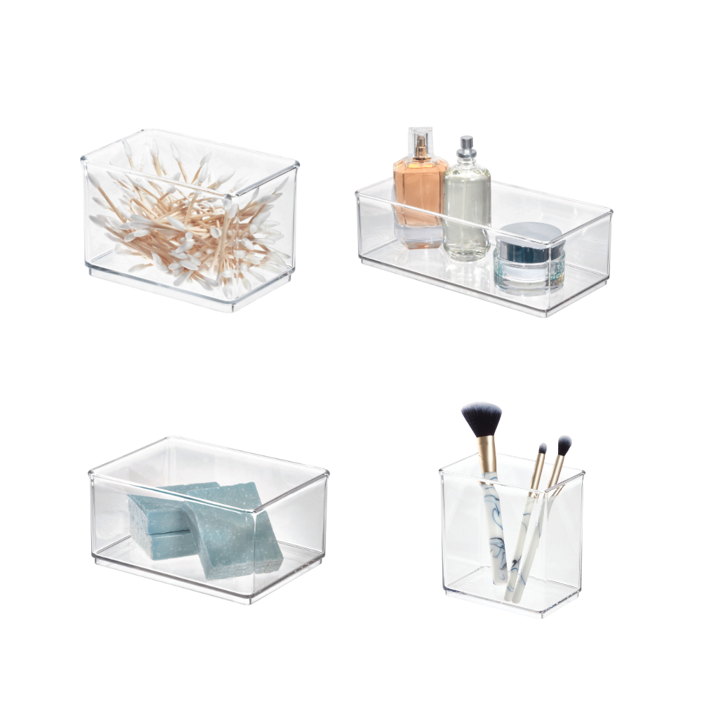 Four transparent plastic boxes containing cotton swabs, perfume, bars of soap, and makeup brushes.