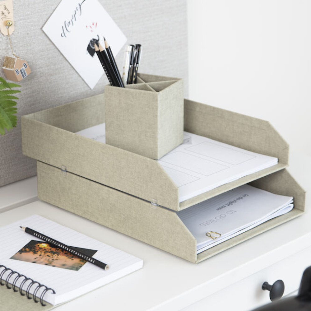 Eine stilvolle Schreibtischeinrichtung mit zwei beigen Bigso HAKAN Dokumentenablage Set 2 Stk. - Linnen Canvas Ablagen mit Dokumenten, einem passenden Stifthalter mit Bleistiften, einem Notizbuch, einem Stift und einer Pflanze für einen organisierten Schreibtisch Organizer Look.