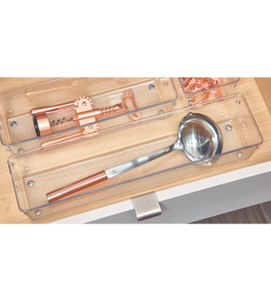 Eine silberne Schöpfkelle mit Kupfergriff und ein kupferner Korkenzieher sind in transparenten Schalen aus dem iDesign Schubladen Organizer-Set LINUS - HOCH (5-teilig) in einer hellen Holzschublade organisiert.