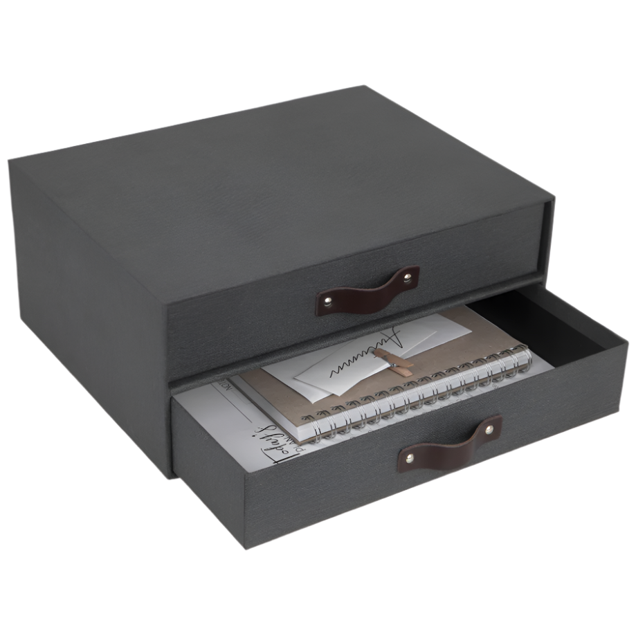 Dunkelgraue Schublade mit Ledergriffen, gefüllt mit Notizbuch und Papieren.