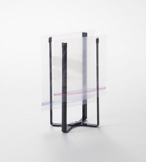 Der YAMAZAKI TOWER Mehrzweckständer Küche - Schwarz hält einen offenen Zip-Top-Beutel aufrecht, um ihn leicht befüllen zu können. Er ist auf einer schlichten weißen Fläche abgebildet.