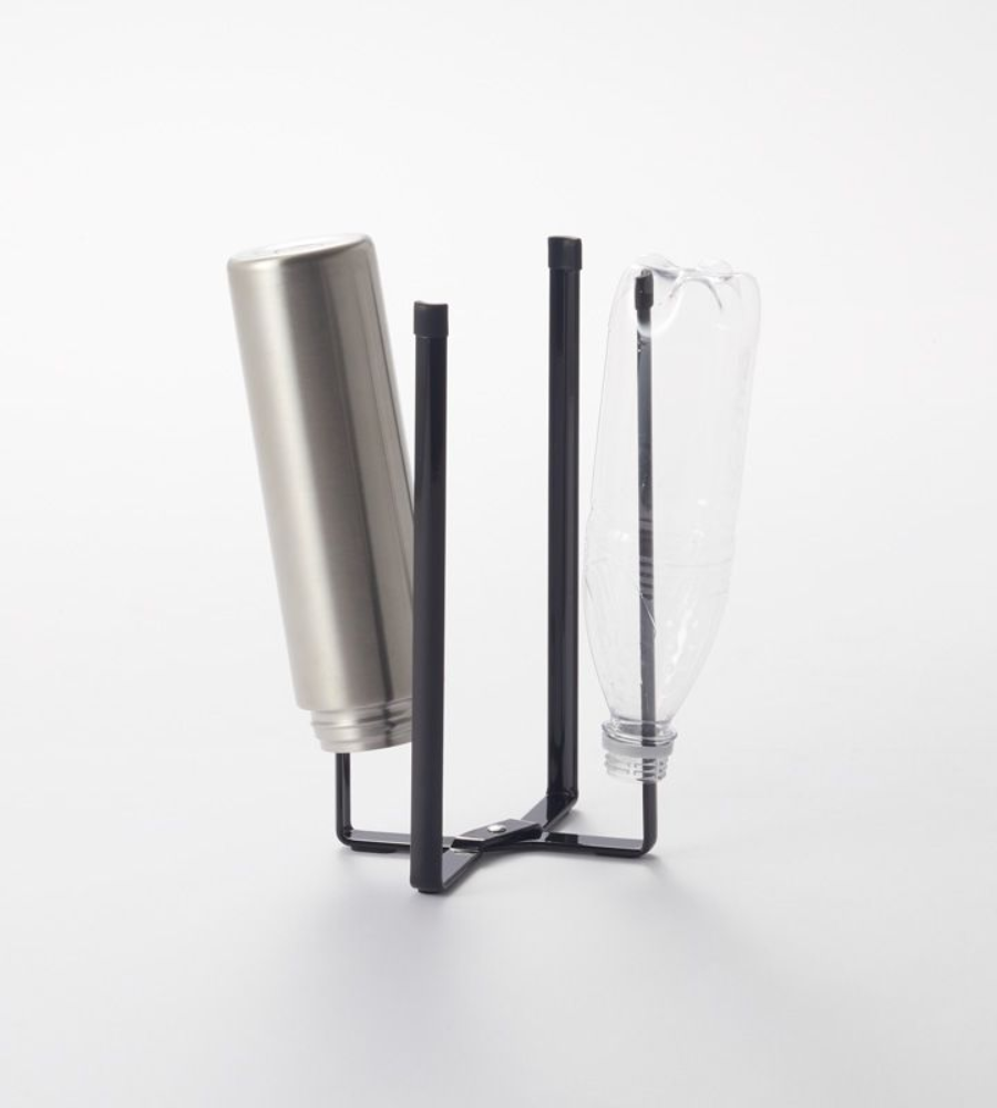Eine schwarze YAMAZAKI TOWER Mehrzweckständer Küche - Schwarz hält eine umgedrehte Edelstahlflasche und eine klare Plastikflasche, die beide vor einem schlichten weißen Hintergrund an der Luft trocknen.
