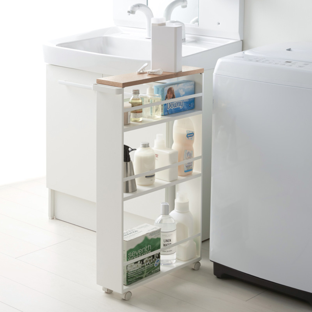 Der TOWER Küchenwagen mit Griff in Weiß von YAMAZAKI dient als schlanker Rollwagen mit Regalböden für Wasch- und Putzmittel, platzsparend zwischen Waschbecken und Maschine im hellen, minimalistischen Waschraum - maximiert Stauraum.